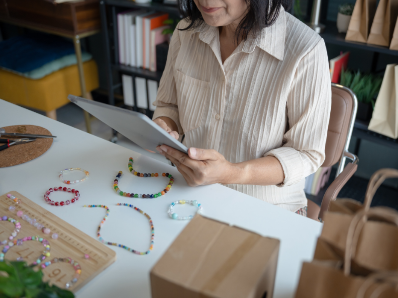 Emprendedora utilizando una tablet para gestionar inventario de productos artesanales, representando el control operativo y el crecimiento sano.